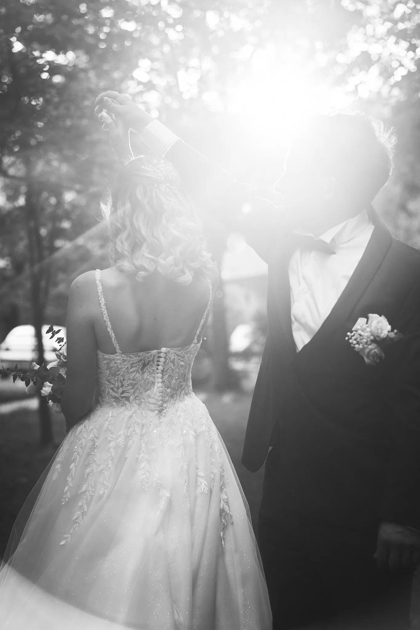 Black-and-white photo of a groom twirling the bride in backlit sunshine