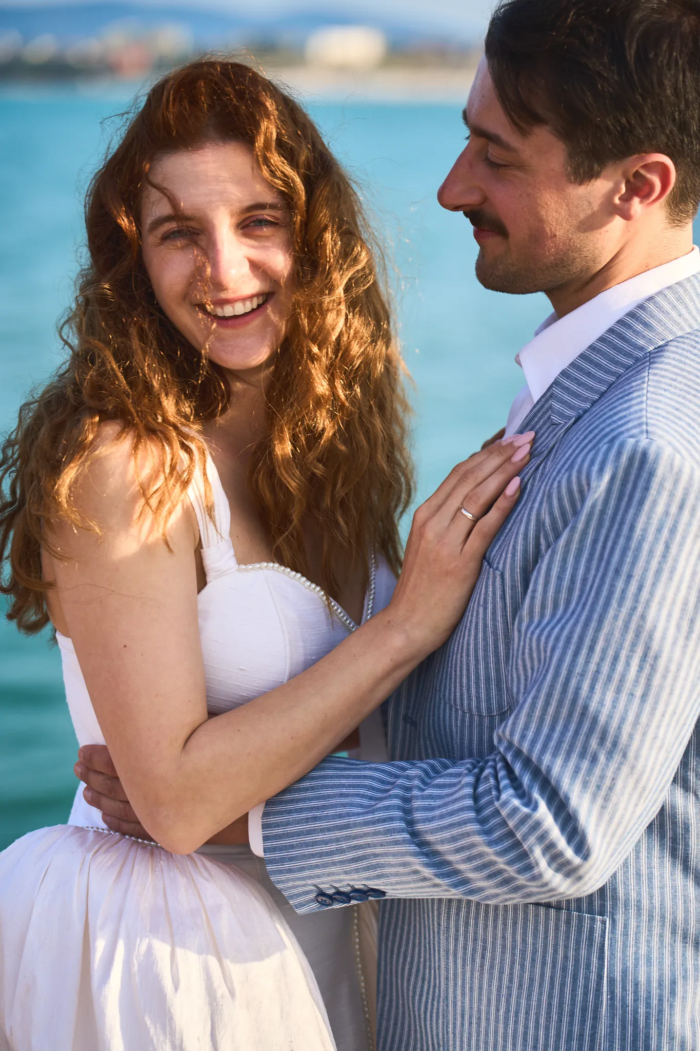 Laughing bride with the groom by the sea