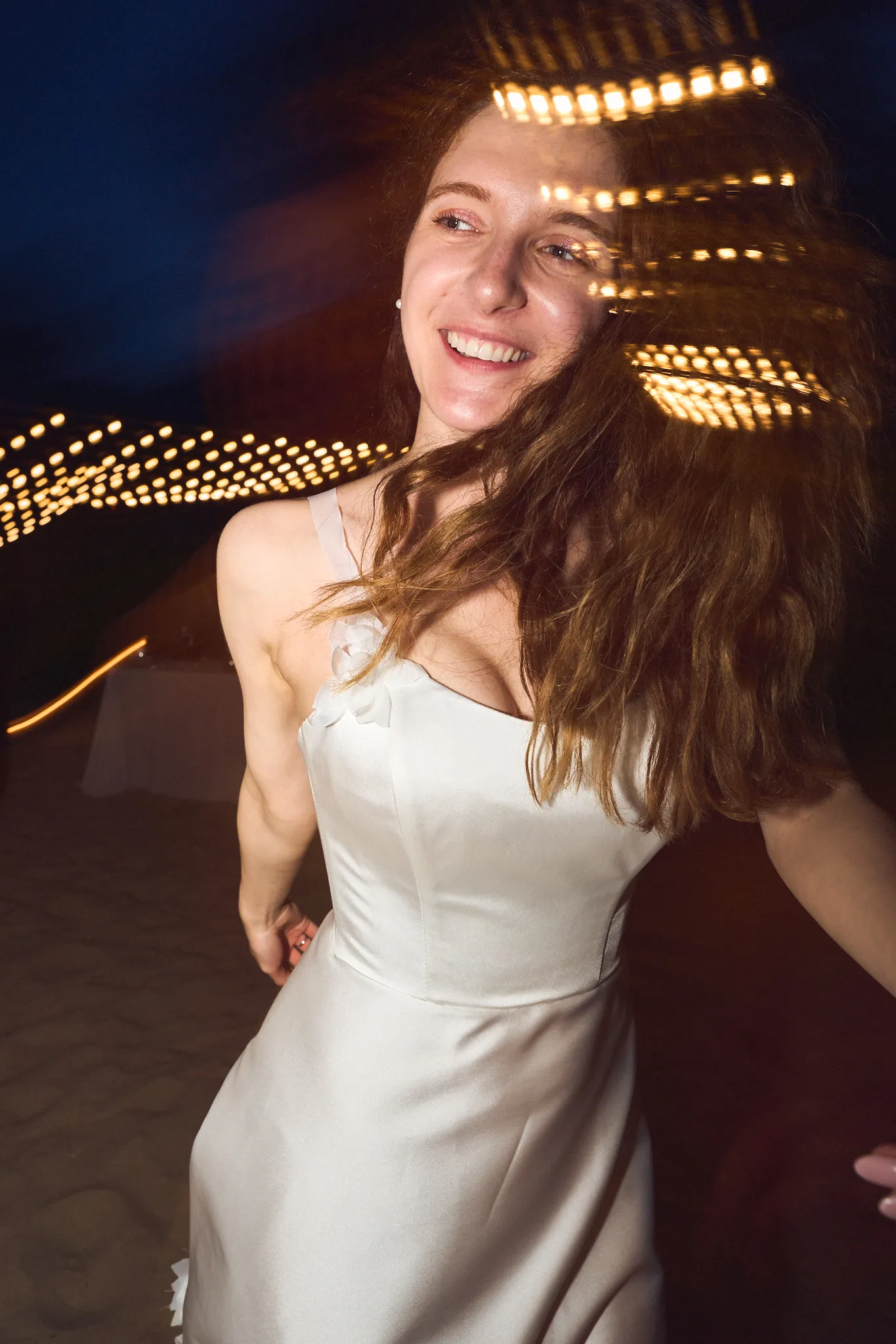 Bride dancing under string lights at night