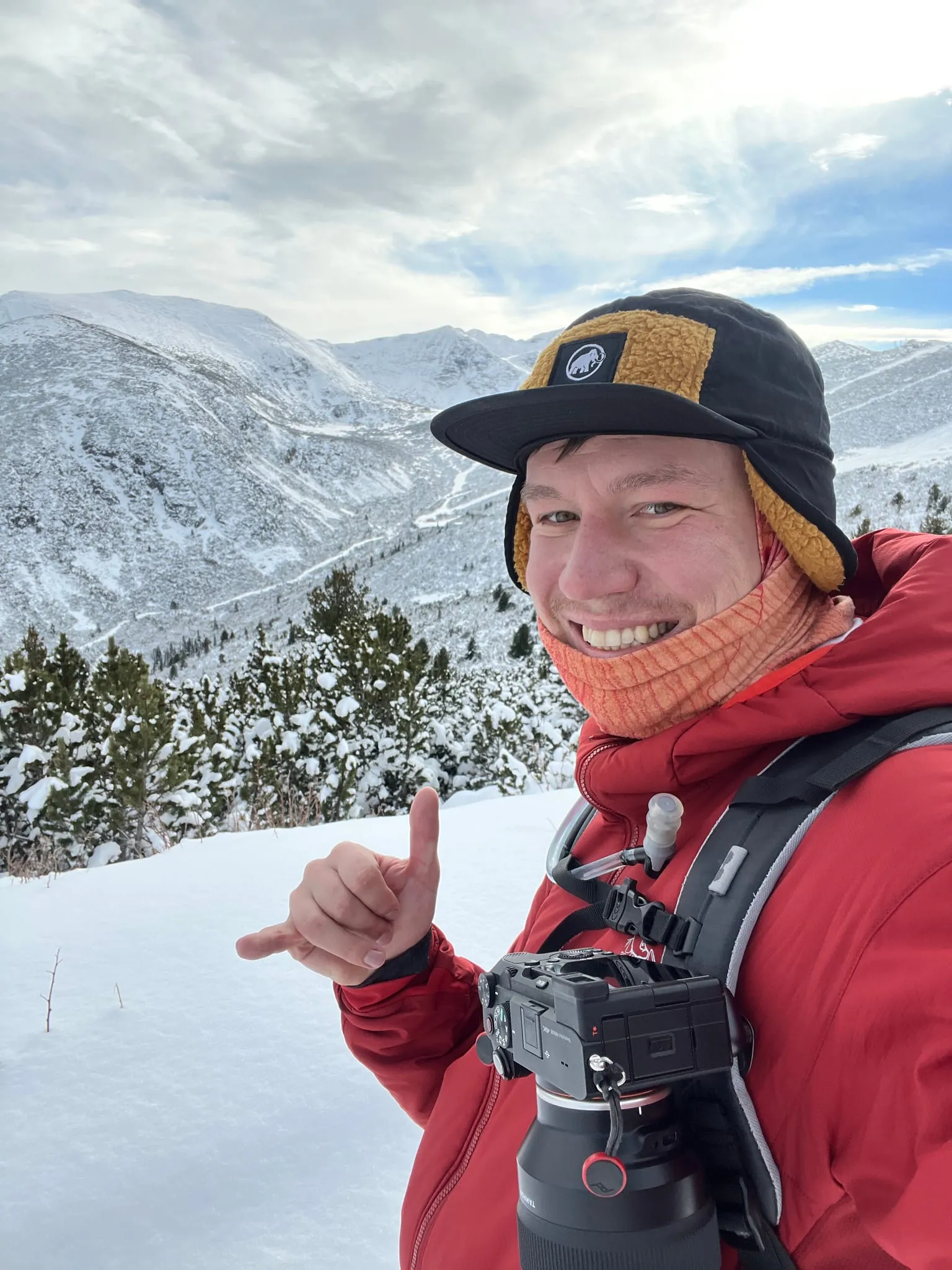 Mihaylo Dimo smiling in the snowy mountains, camera on his shoulder